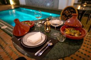 une table avec une assiette de nourriture et des verres de vin dans l'établissement The Grand Riad and Spa, à Marrakech