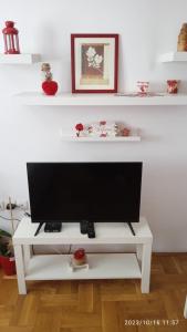 uma televisão numa banca de televisão branca numa sala de estar em Apartman Mira em Pozarevac