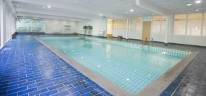 - une grande piscine avec des carreaux bleus dans un bâtiment dans l'établissement Bilderberg Hotel 't Speulderbos, à Garderen