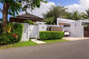 una casa blanca con una valla y un coche en Luxury villa with pool and garden - BL #93, en Phuket