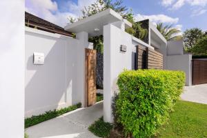 una casa blanca con un seto verde en Luxury villa with pool and garden - BL #93, en Phuket