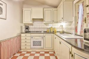 - une cuisine avec des placards blancs et un sol en damier dans l'établissement Casa Nobile - Together in Tuscany, à Cortone