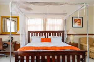 ein Schlafzimmer mit einem Himmelbett mit einer orangefarbenen Decke in der Unterkunft Malabi Exclusive Lodges in Lilongwe