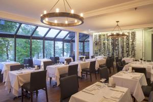 a restaurant with white tables and chairs and windows at L'Auberge Du Lac St-Pierre in Trois-Rivières