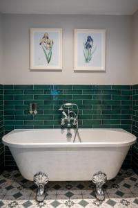 a bath tub in a bathroom with green tiles at Ethorpe Hotel by Chef & Brewer Collection in Gerrards Cross