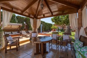 un patio esterno con pergolato in legno, tavolo e sedie di Villa Torres Motril a Motril
