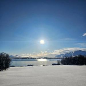 een uitzicht op een meer met de zon in de lucht bij Peaceful small house by the sea in Tromsø