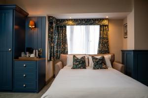 een slaapkamer met een bed met blauwe kasten en een raam bij Ethorpe Hotel by Chef & Brewer Collection in Gerrards Cross