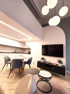 ein Wohnzimmer mit Tischen und Stühlen und einem Flachbild-TV in der Unterkunft Central Gallery Apartment in Debrecen