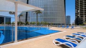Maison Privee - Elegant & Panoramic Sea View Apt on Al Reem Island في أبوظبي: مسبح مع كراسي جلوس بجانب مبنى