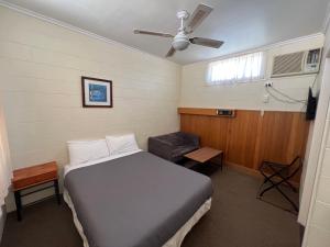 1 dormitorio con 1 cama, ventana y ventilador en Glossop Motel, en Winkie