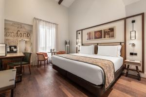 um quarto de hotel com uma cama grande e uma secretária em Áurea Toledo by Eurostars Hotel company em Toledo