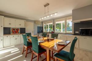 Una cocina con una mesa de madera y sillas verdes. en Maison Carrosse - A 20min de Bordeaux, en Martillac