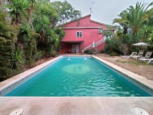 una piscina di fronte a una casa rossa di Casa rural en el campo con animales, piscina y barbacoa ad Almodóvar del Río