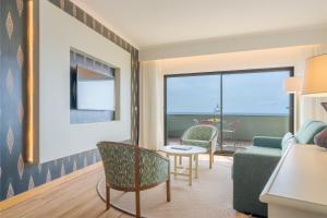 een woonkamer met een bank en een tafel en stoelen bij Pestana Vila Lido Madeira Ocean Hotel in Funchal