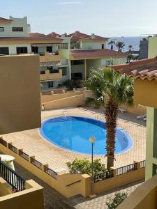 - une piscine avec un palmier à côté d'un bâtiment dans l'établissement Duplex con piscina cerca del mar, à Puertito de Güímar