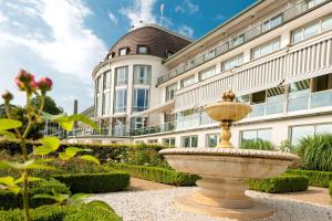 einen Brunnen in einem Garten vor einem Gebäude in der Unterkunft Parkhotel Bremen – ein Mitglied der Hommage Luxury Hotels Collection in Bremen