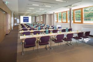 una sala de conferencias con mesas largas y sillas púrpuras en Dorint Thermenhotel Freiburg, en Freiburg im Breisgau
