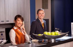 Dos mujeres de pie en una cocina con un tazón de fruta en Essential by Dorint Frankfurt-Niederrad, en Frankfurt