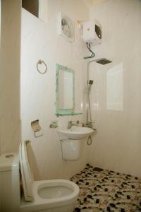 a white bathroom with a toilet and a sink at Phong Nha Tuan Garden House in Phong Nha