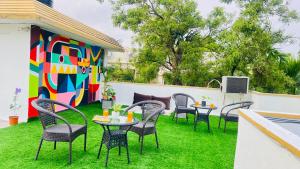 eine Terrasse mit Stühlen, Tischen und einer farbenfrohen Wand in der Unterkunft Olive Serviced Apartments Salt Lake Kolkata in Kalkutta