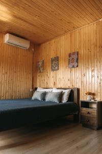 1 dormitorio con 1 cama en una pared de madera en СИНІ ВОДИ база відпочинку 