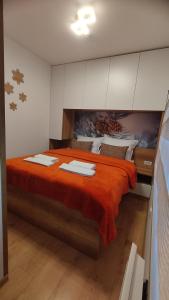a bedroom with a large bed with orange sheets at Vila Jahor Apartmani Dis 7 i 8 in Jahorina