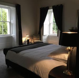 a bedroom with a large bed and two windows at Leirsinn Mhor in Killin