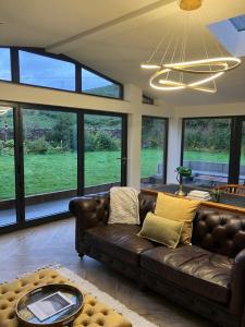 a living room with a brown leather couch and large windows at Leirsinn Mhor in Killin +8 photos