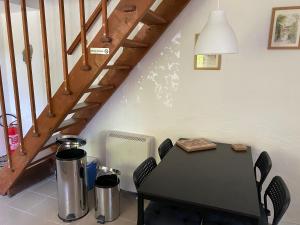 a black table and chairs in a room with stairs at Le petit gîte blanc, Langourla in Langourla