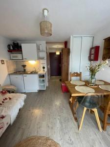 een kleine woonkamer met een tafel en een keuken bij Chaleureux Studio Montagnard avec balcon in Prémanon