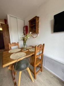 een houten tafel met stoelen en een vaas met bloemen erop bij Chaleureux Studio Montagnard avec balcon in Prémanon