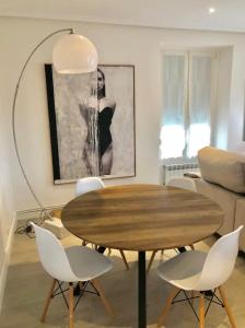 Una sala de estar con una mesa de madera y sillas blancas. en Lovely port apártement, en San Sebastián