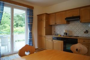 a kitchen with wooden cabinets and a large window at Haus Kollin in Keutschach am See