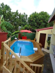 uma piscina com um deque de madeira e um guarda-sol em Sunbeachparadise em Port-Louis
