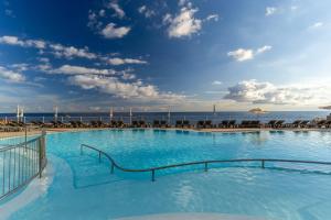 a swimming pool with chairs and the ocean in the background at Pestana Vila Lido Madeira Ocean Hotel in Funchal