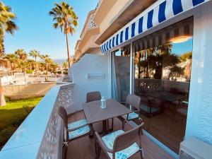 a table and chairs on a balcony with palm trees at La Perla in Playa de las Americas