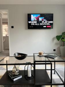 uma sala de estar com uma mesa e uma televisão na parede em Stunning apartment in Beckton with Private Entrance em Londres