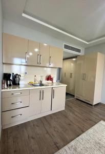 an empty kitchen with white cabinets and wooden floors at BUREAU RESİDENCE STÜDYO DAİRE in Kartepe