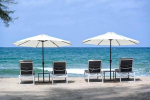 a group of chairs and umbrellas on the beach at Amora Beach Resort Phuket - SHA Extra Plus in Bang Tao Beach