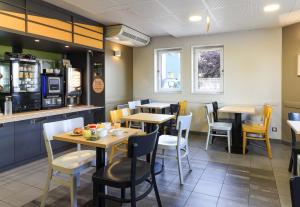 un restaurant avec des tables, des chaises et un comptoir dans l'établissement B&B HOTEL Dijon Les Portes du Sud, à Dijon