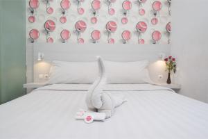 a white bed with a stuffed animal on it at Red Orchid Hotel by Sajiwa in Semarang