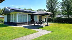 a house with an umbrella and a table and chairs at Bungalow Bavelds Home - Denekamp in Denekamp