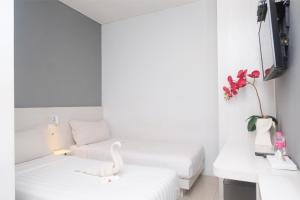 a white room with two beds and a swan on a stool at Red Orchid Hotel by Sajiwa in Semarang