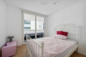 a white bedroom with a white bed with a red pillow at EXQUIS Design 2BR Apartment BAUHAUS I Balkon I Parkplatz I Top-Lage I Mercedes-Benz I Kinderbetten in Böblingen