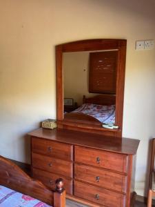 een slaapkamer met een houten dressoir met een spiegel bij Evie's House Arakapas in Arakapas