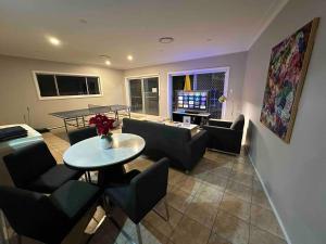 a living room with a table and chairs and a tv at 5 Bedroom 3 bathroom House with Pool, Spa, Voice-Control Smart Home and Game Room in Sydney