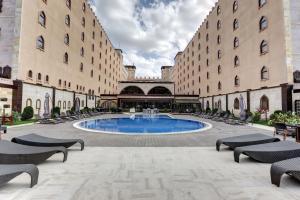 un gran patio con piscina frente a 2 edificios en Suhan Cappadocia Hotel & Spa, en Avanos