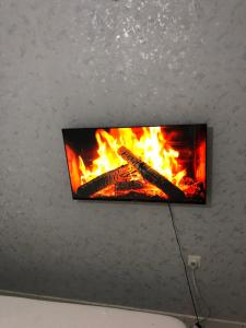 a flat screen tv hanging on a wall with a fire at Chillhaushomes in Mombasa