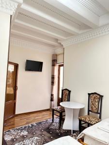 Habitación con 2 sillas y TV en la pared. en Hotel Mironshox, en Bukhara